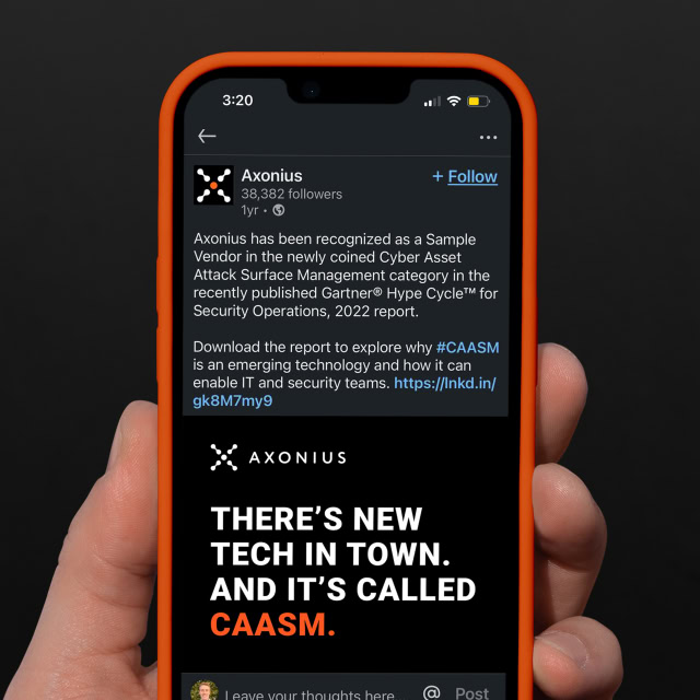 Person holding a phone displaying a LinkedIn post by Axonius, highlighting its recognition in Gartner's Hype Cycle report for cybersecurity. The post advertises CAASM technology.